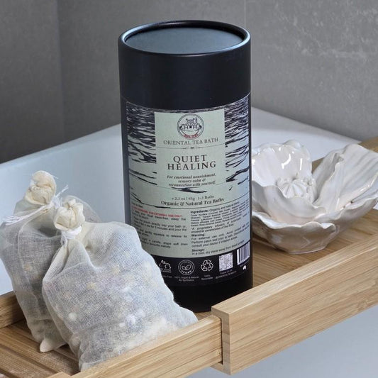 Tea canister labeled 'Quiet Healing' on a wooden shelf with tea bags.